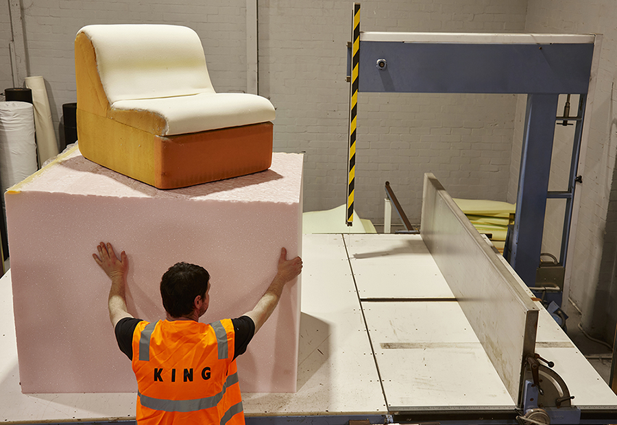King Living employee pictured in front of large foam cutting technology for sustainable sofa recovering and repair process.