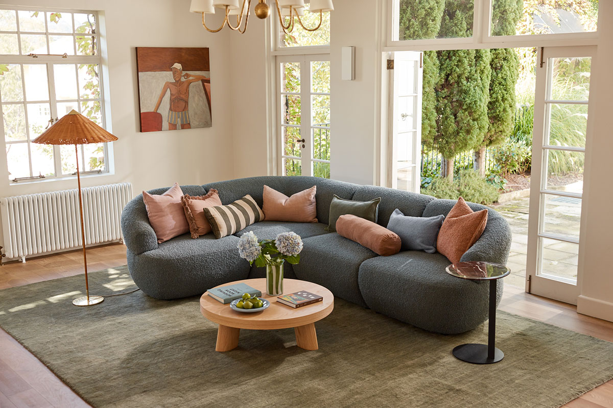 A small modern living room with a blue sofa styled with various cushions.